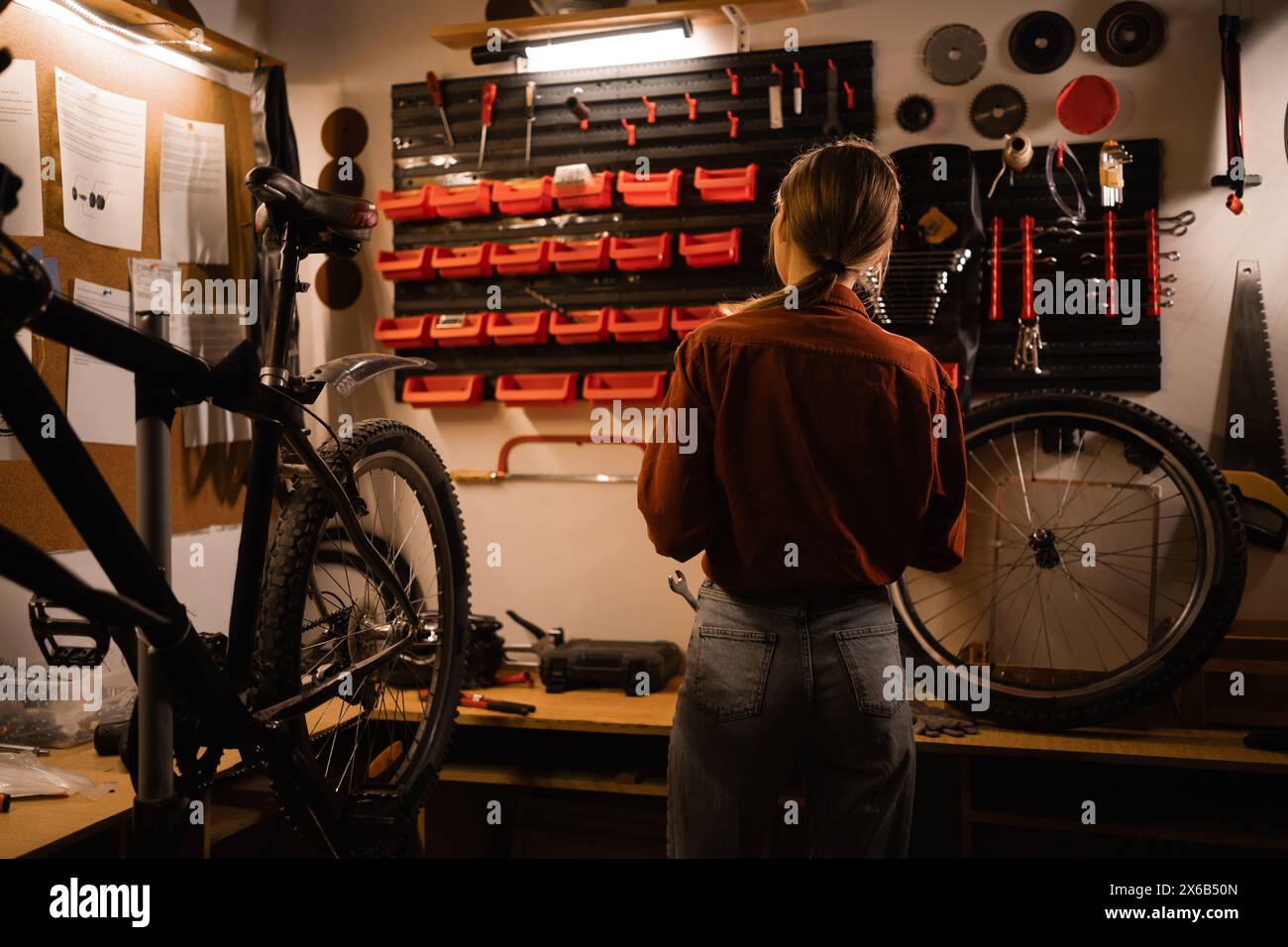 Rear view of a young woman in a garage. Bicycle repair and maintenance concept Stock Photo