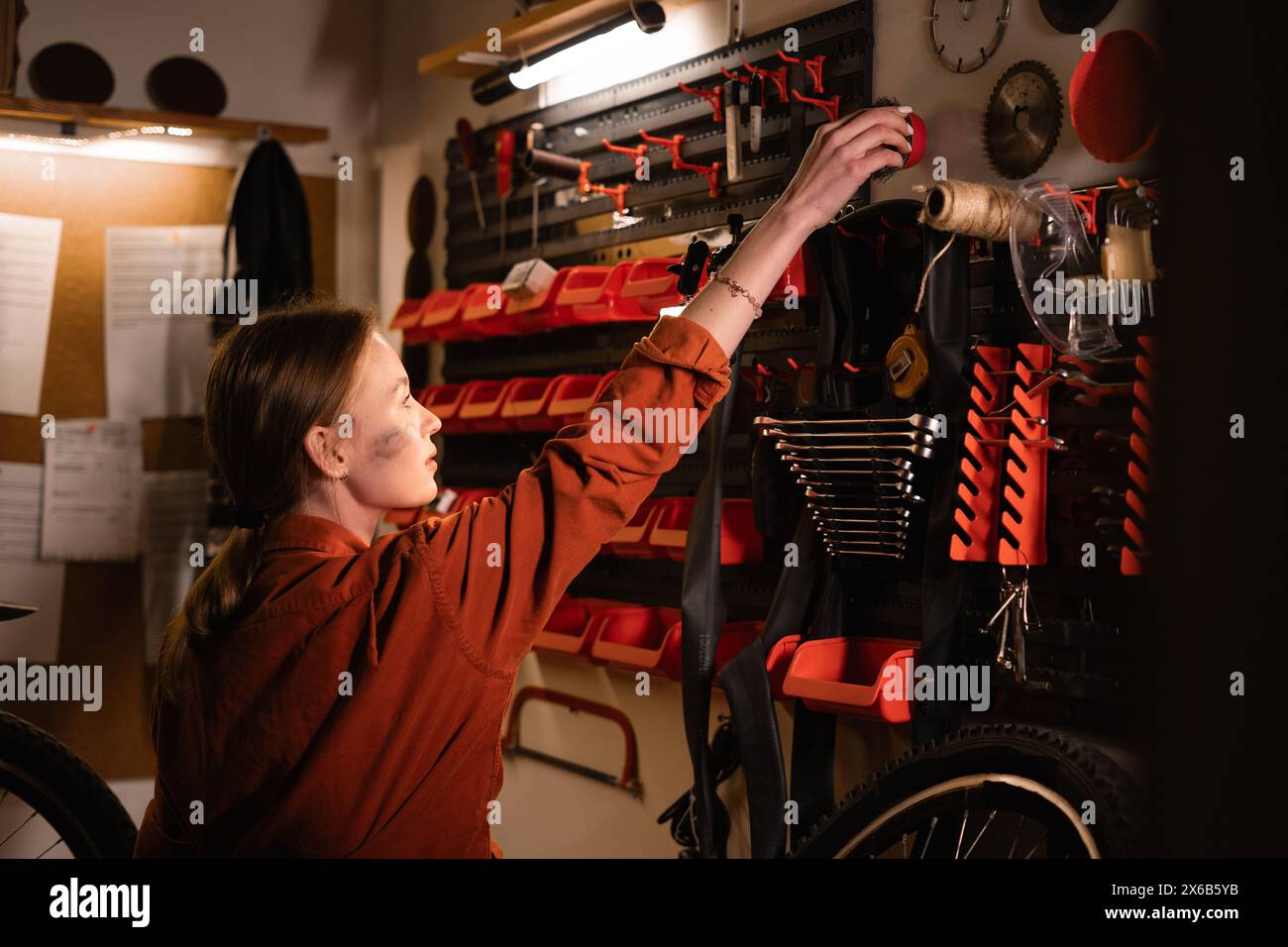 Portrait of woman mechanic in garage or workshop inspecting tools during the bike maintenance Stock Photo