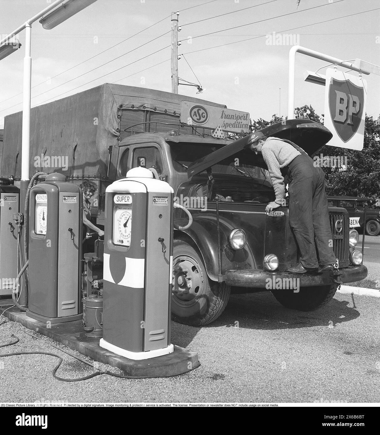 Petrol station in the olden days. Here, a truck driver from the company ASG has stopped and opened the hood of his Volvo truck. The petrol station belongs to the English petroleum company BP (British Petroleum). The company's operations with its own gas stations in Sweden were discontinued in 1994 and most BP petrol stations became Statoil petrol stations. 1959. Roland Palm ref 10-72-5 Stock Photo