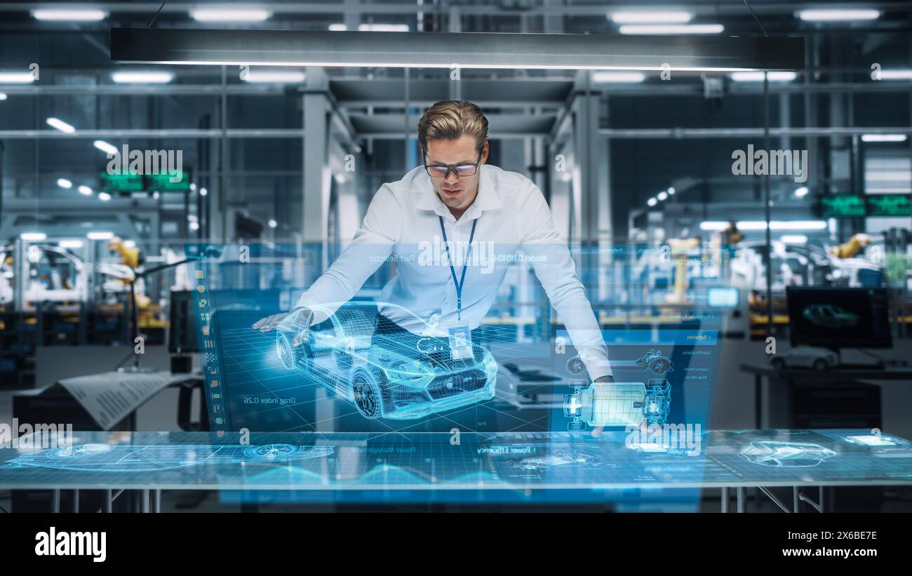 Confident Engineer Working on a New Electric Car with Use of Augmented Reality Hologram in an Office at Car Assembly Plant. Industrial Specialist Working in Technological Vehicle Development Facility. Stock Photo