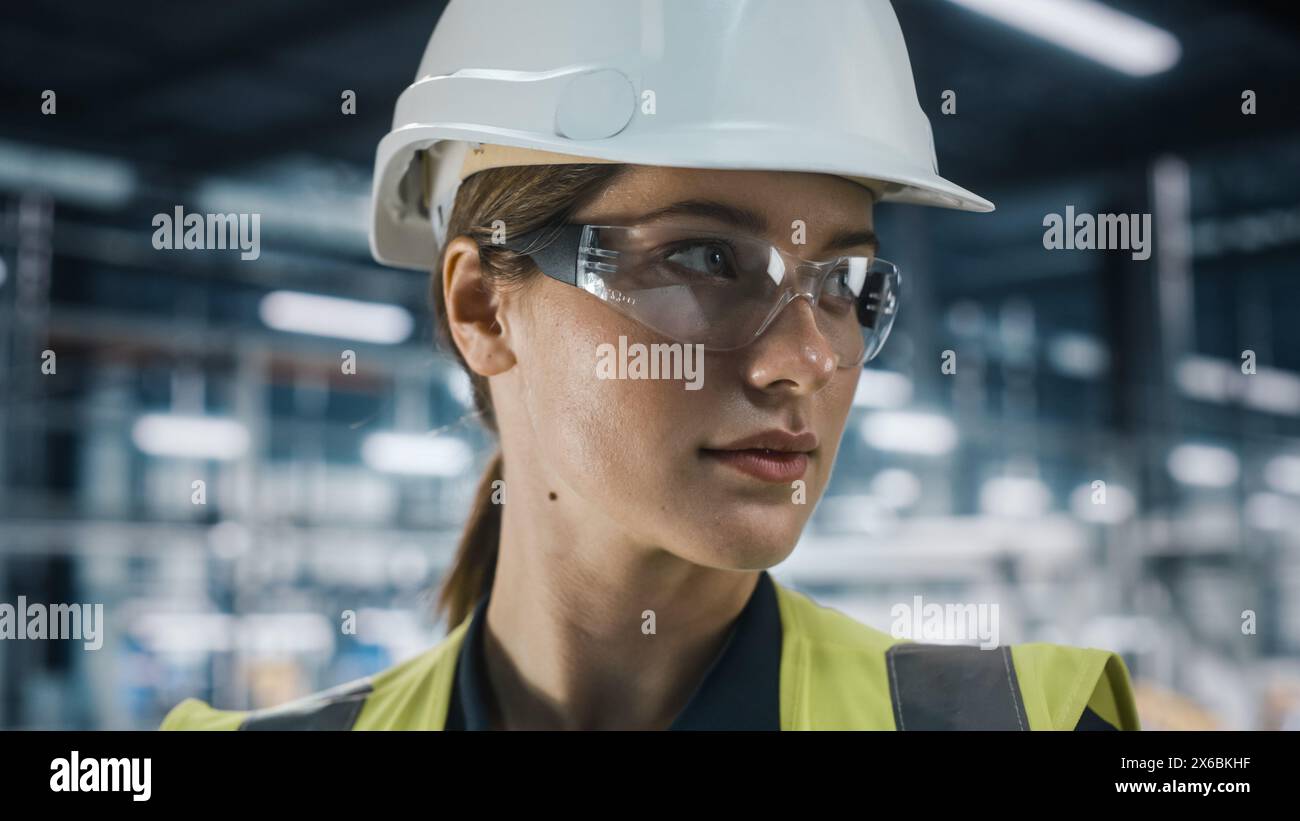 Portrait of Female Automotive Industry Engineer Wearing Safety Glasses and High Visibility Vest at Car Factory Facility. Confident Assembly Plant Specialist Working on Manufacturing Modern Vehicles. Stock Photo