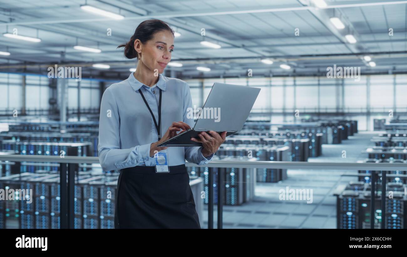 Data Center Engineer Using Laptop Computer. Server Farm Cloud Computing Specialist Facility with Multiethnic Female System Administrator Working with Data Protection Network for Cyber Security. Stock Photo