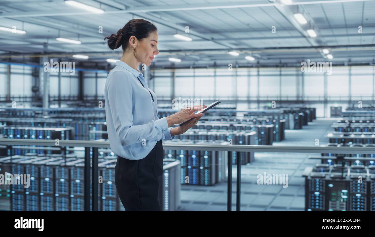 Data Center Engineer Using Tablet Computer. Server Farm Cloud Computing Specialist Facility with Multiethnic Female System Administrator Working with Data Protection Network for Cyber Security. Stock Photo