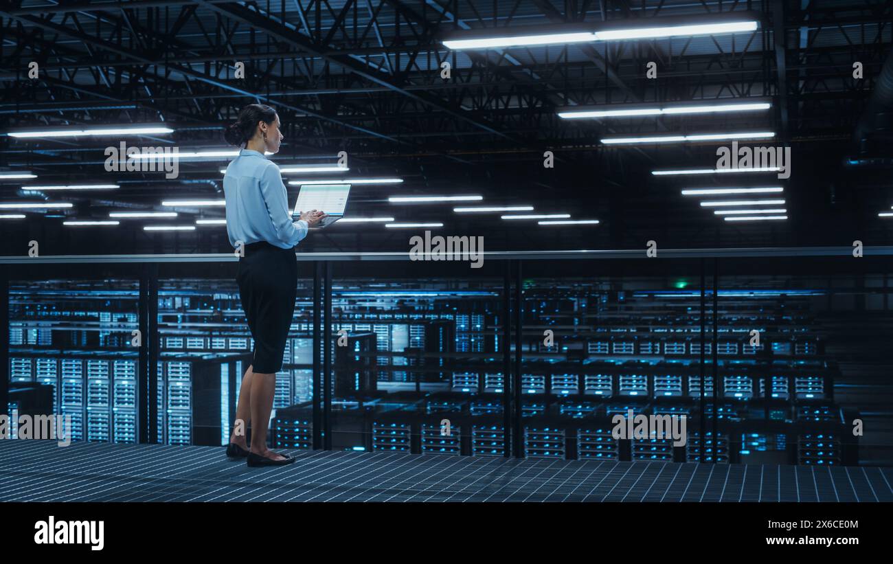 Data Center Engineer Using Laptop Computer. Server Farm Cloud Computing Specialist Facility with Multiethnic Female System Administrator Working with Data Protection Network for Cyber Security. Stock Photo