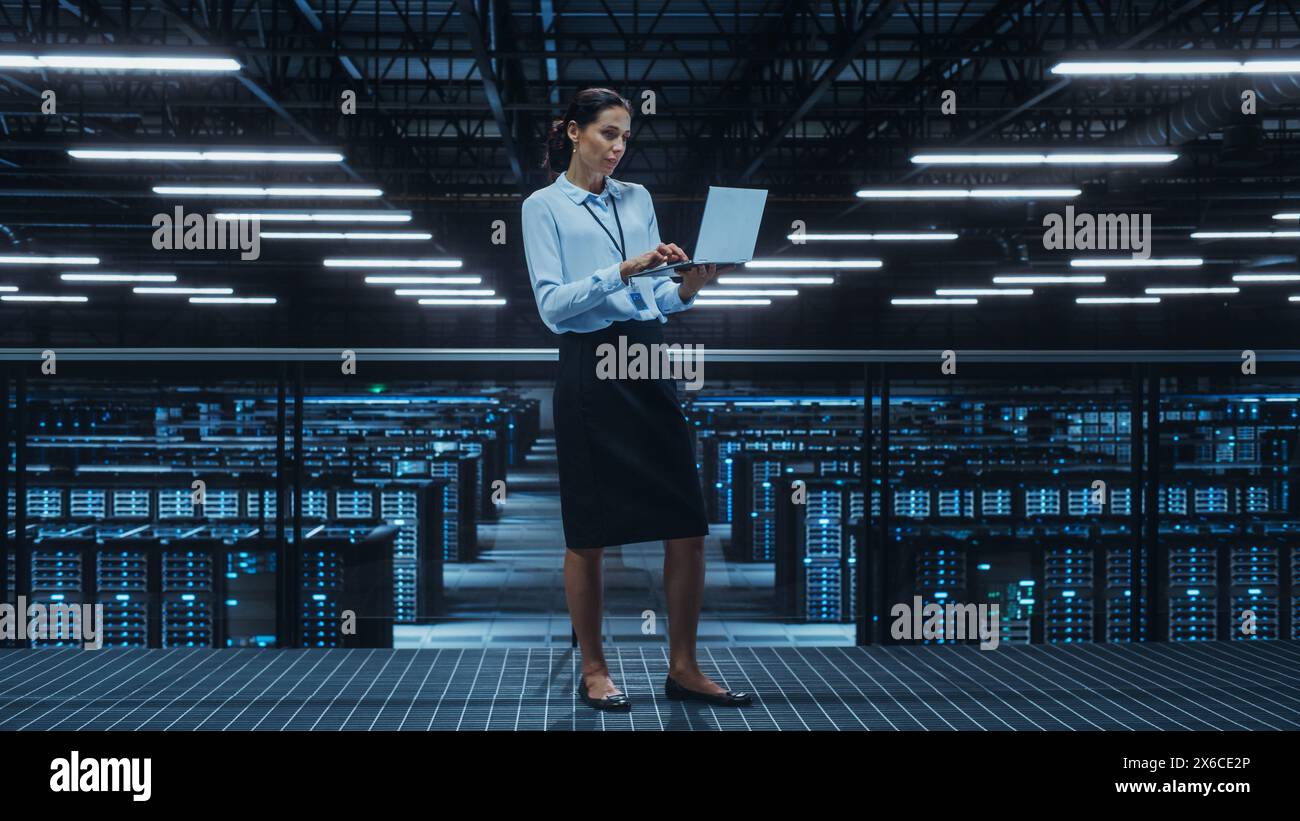 Data Center Engineer Using Laptop Computer. Server Farm Cloud Computing Specialist Facility with Multiethnic Female System Administrator Working with Data Protection Network for Cyber Security. Stock Photo