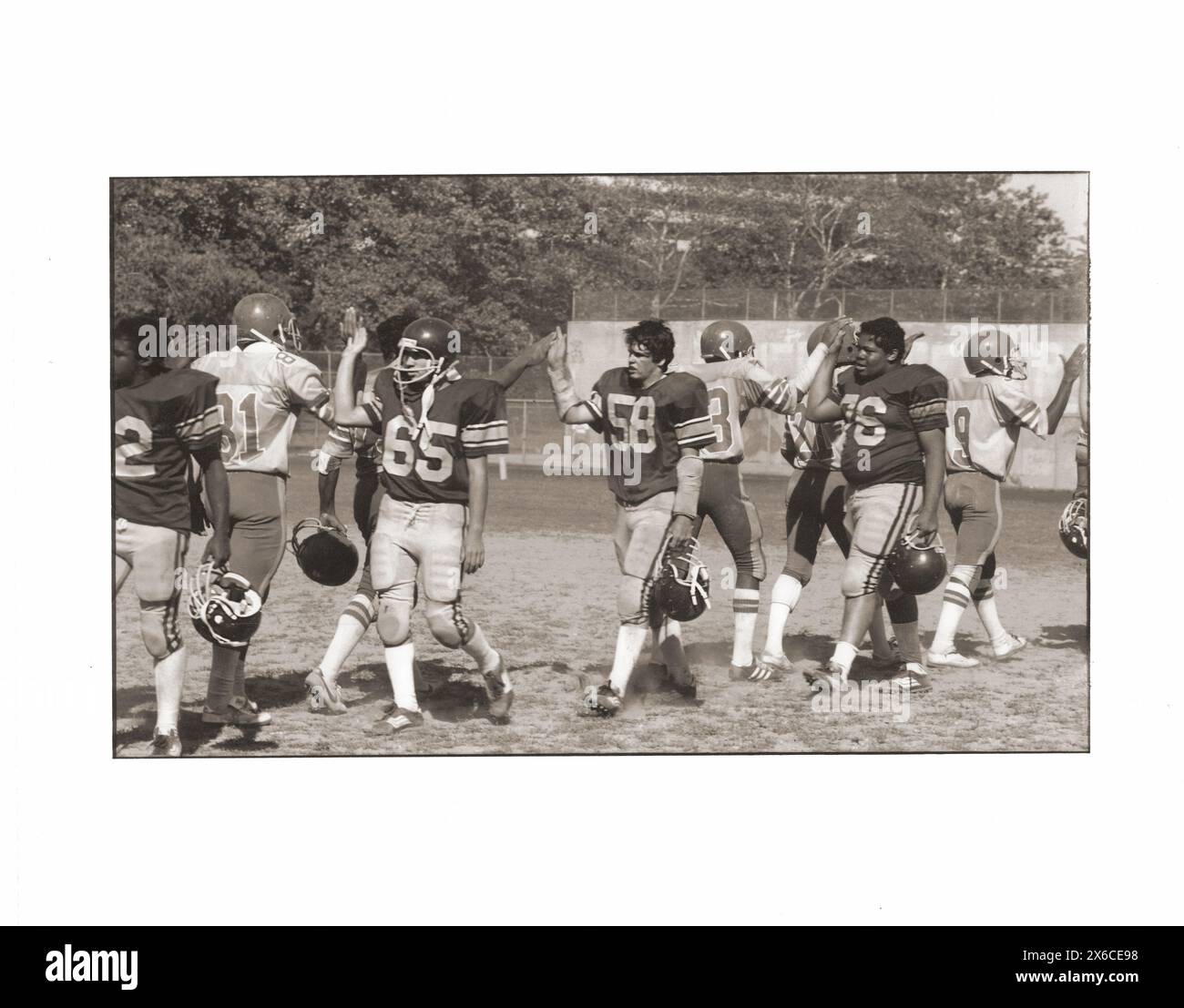 SPORTSMANSHIP. After a 1982 high school football game, participating players high five with opposing players. At Midwood Field in Brooklyn, New York. Stock Photo