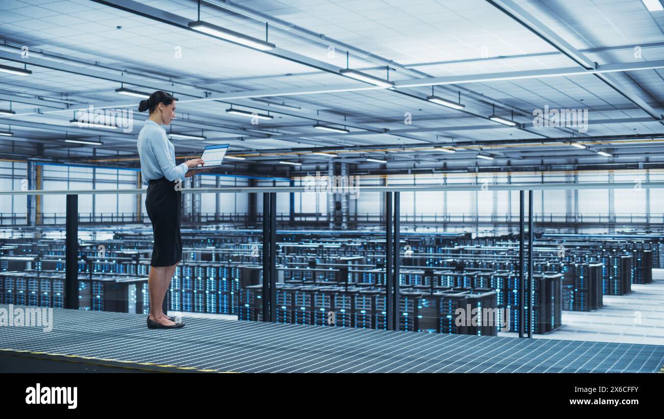 Data Center Engineer Using Laptop Computer. Server Farm Cloud Computing Specialist Facility with Multiethnic Female System Administrator Working with Data Protection Network for Cyber Security. Stock Photo