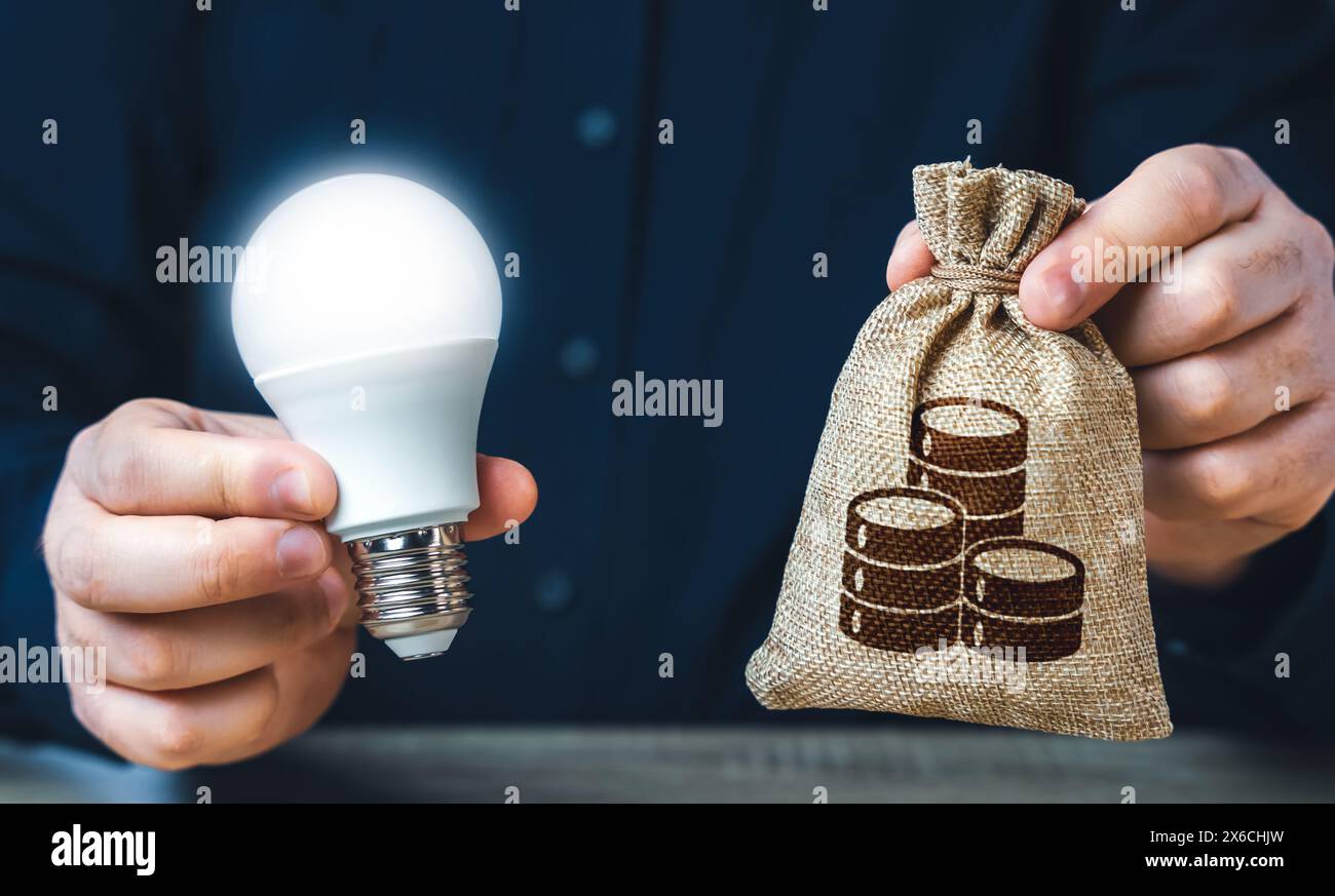 Businessman holding a glowing light bulb and a money bag. Investment in an idea. Reduce carbon footprint. Offering financial incentives to enhancing e Stock Photo
