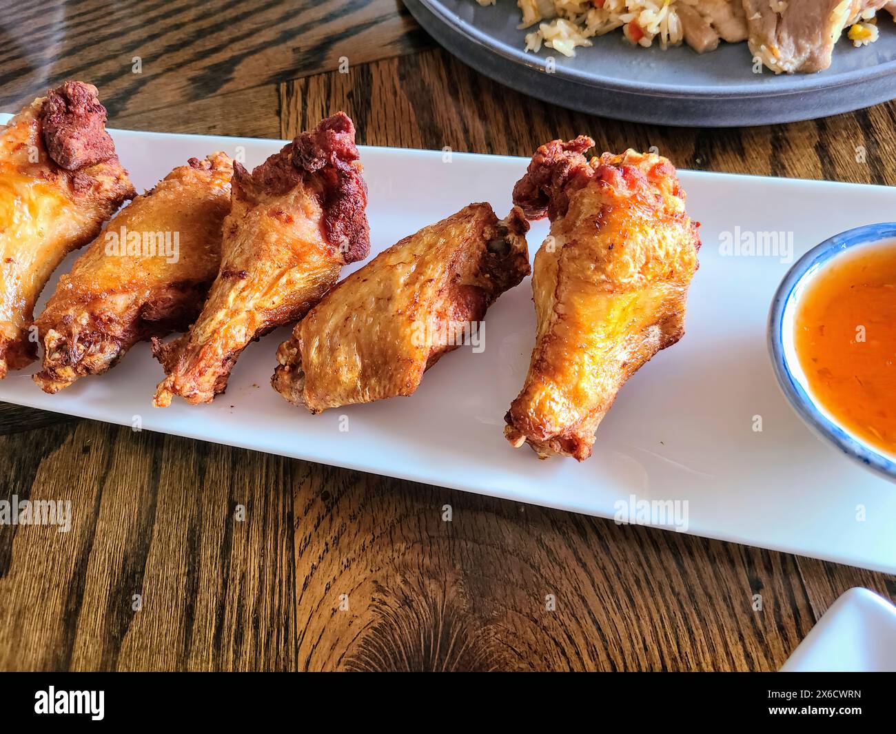 Crispy Fried Chicken with Spicy Sauce in Casual Dinner Setting, Eye-Level View Stock Photo