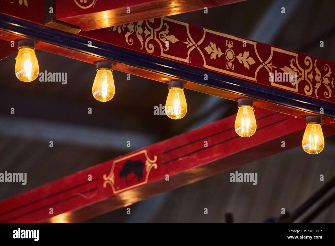 Ornate Beam with Cultural Motifs and Hanging Bulbs, Upward View Stock Photo
