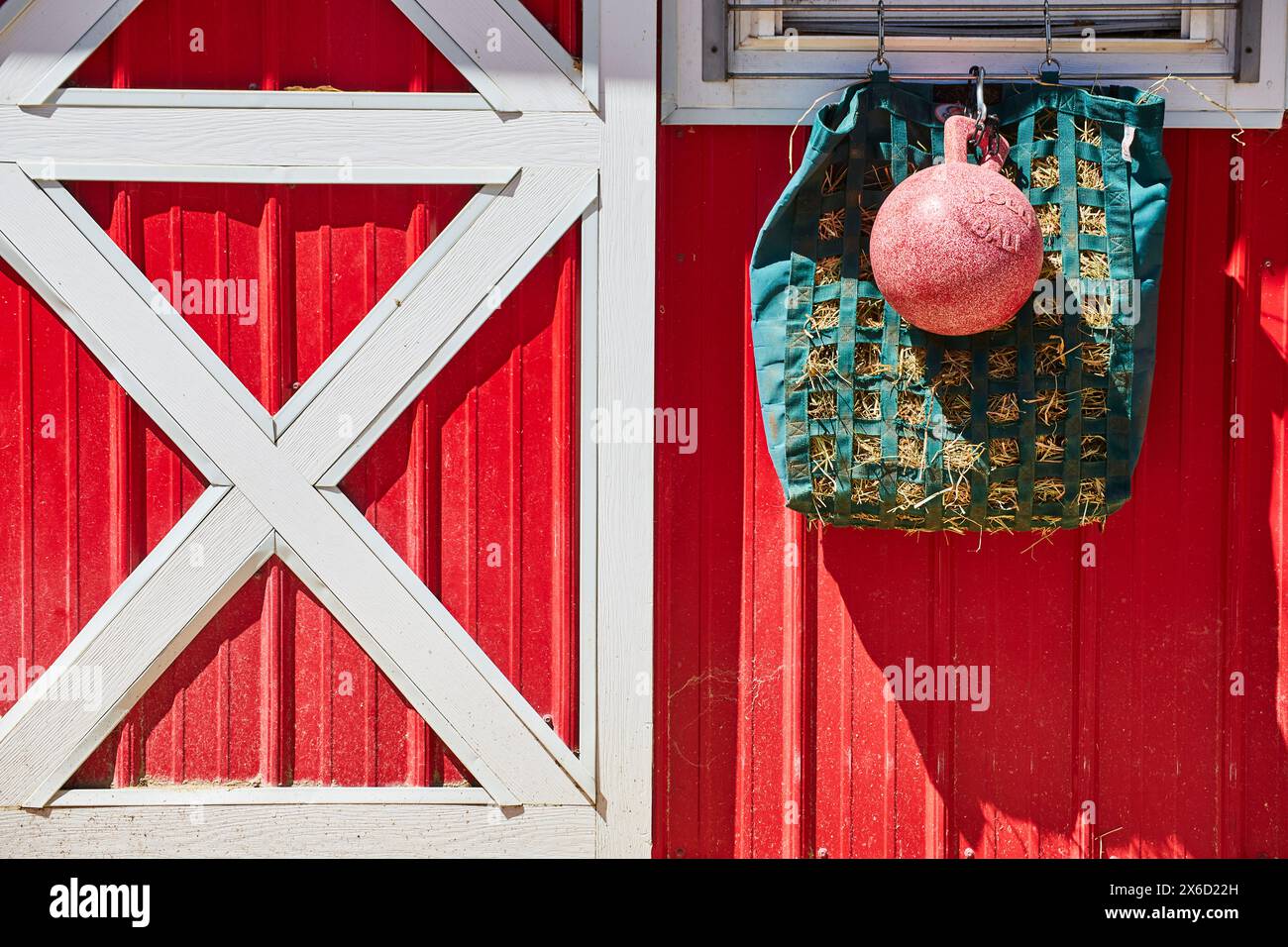 Vibrant Red Barn Door with Weight and Hay Bag, Rural Farm Decor Stock Photo