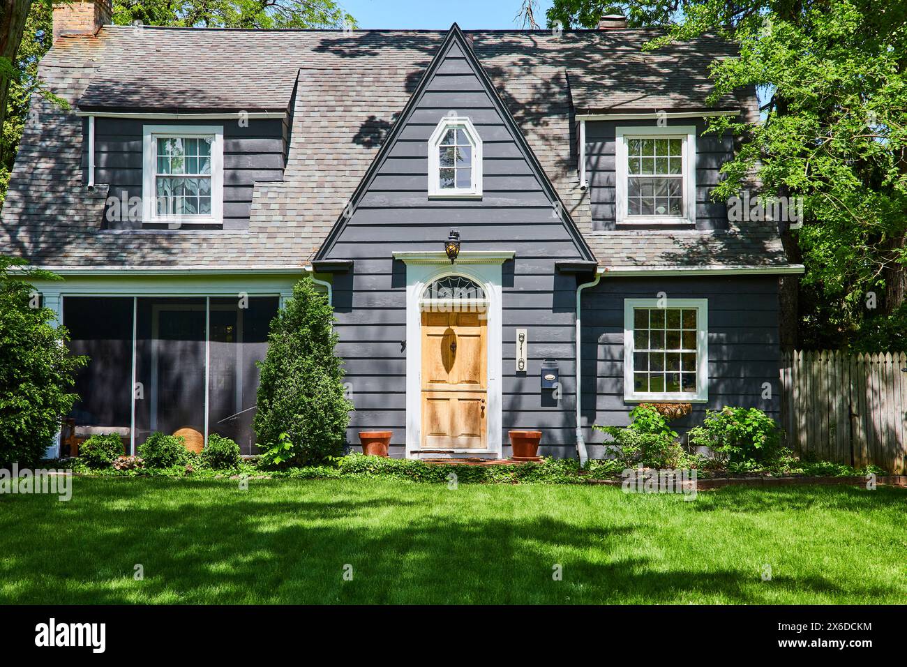 Traditional Two-Story Gray House with Lush Lawn and Terracotta Pots Stock Photo
