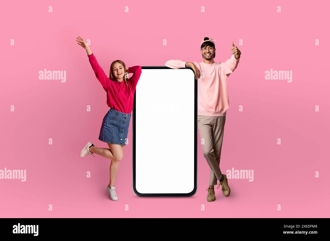 Two Happy Friends Posing Next to a Large Smartphone Stock Photo
