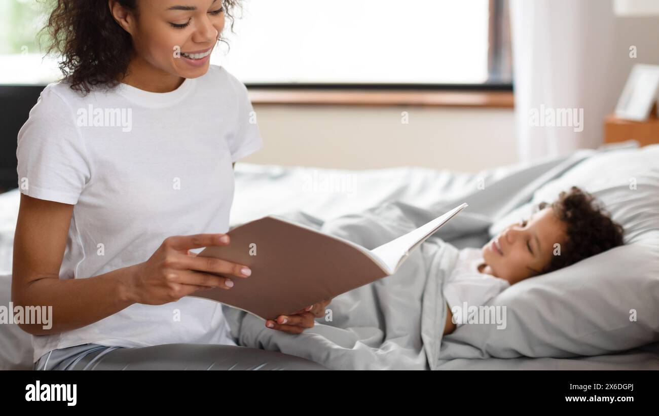 Cheerful Mother Reading Story to Her Child in Bed Stock Photo