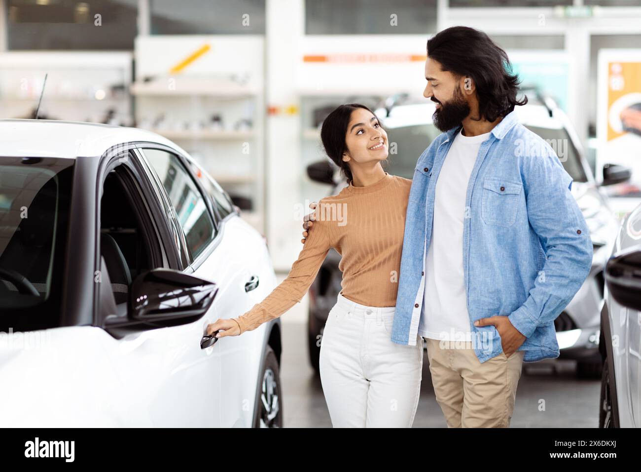 Man and Woman Standing Next to Car at Showroom Stock Photo