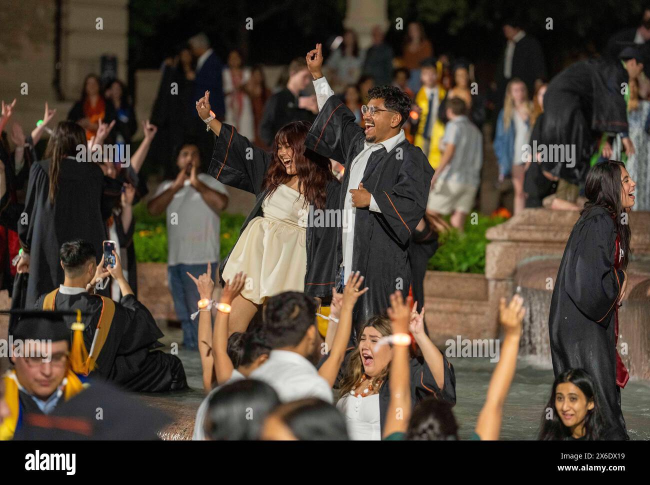 Austin Texas USA, May 11 2024: New University of Texas at Austin graduates wade and splash in the Littlefield Fountain immediately after their commencement ceremony held nearby in the school's football stadium. The celebratory dunk is a long-standing campus tradition. ©Bob Daemmrich Stock Photo