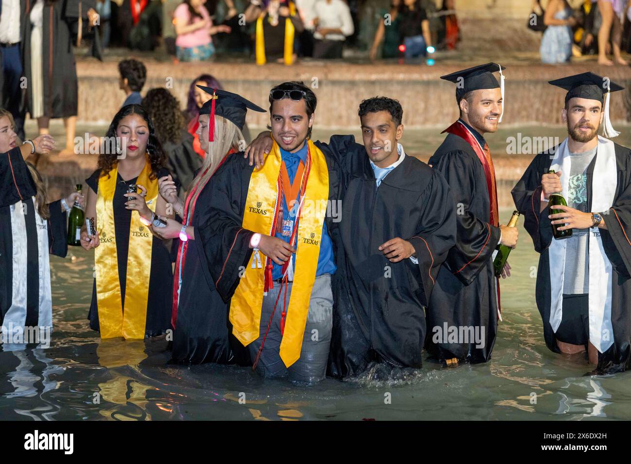 Austin Texas USA, May 11 2024: New University of Texas at Austin graduates wade and splash in the Littlefield Fountain immediately after their commencement ceremony held nearby in the school's football stadium. The celebratory dunk is a long-standing campus tradition. ©Bob Daemmrich Stock Photo