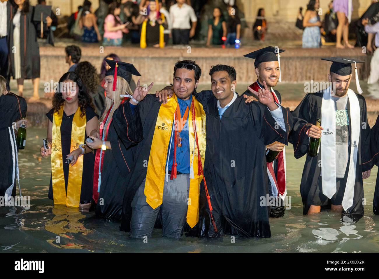 Austin Texas USA, May 11 2024: New University of Texas at Austin graduates wade and splash in the Littlefield Fountain immediately after their commencement ceremony held nearby in the school's football stadium. The celebratory dunk is a long-standing campus tradition. ©Bob Daemmrich Stock Photo