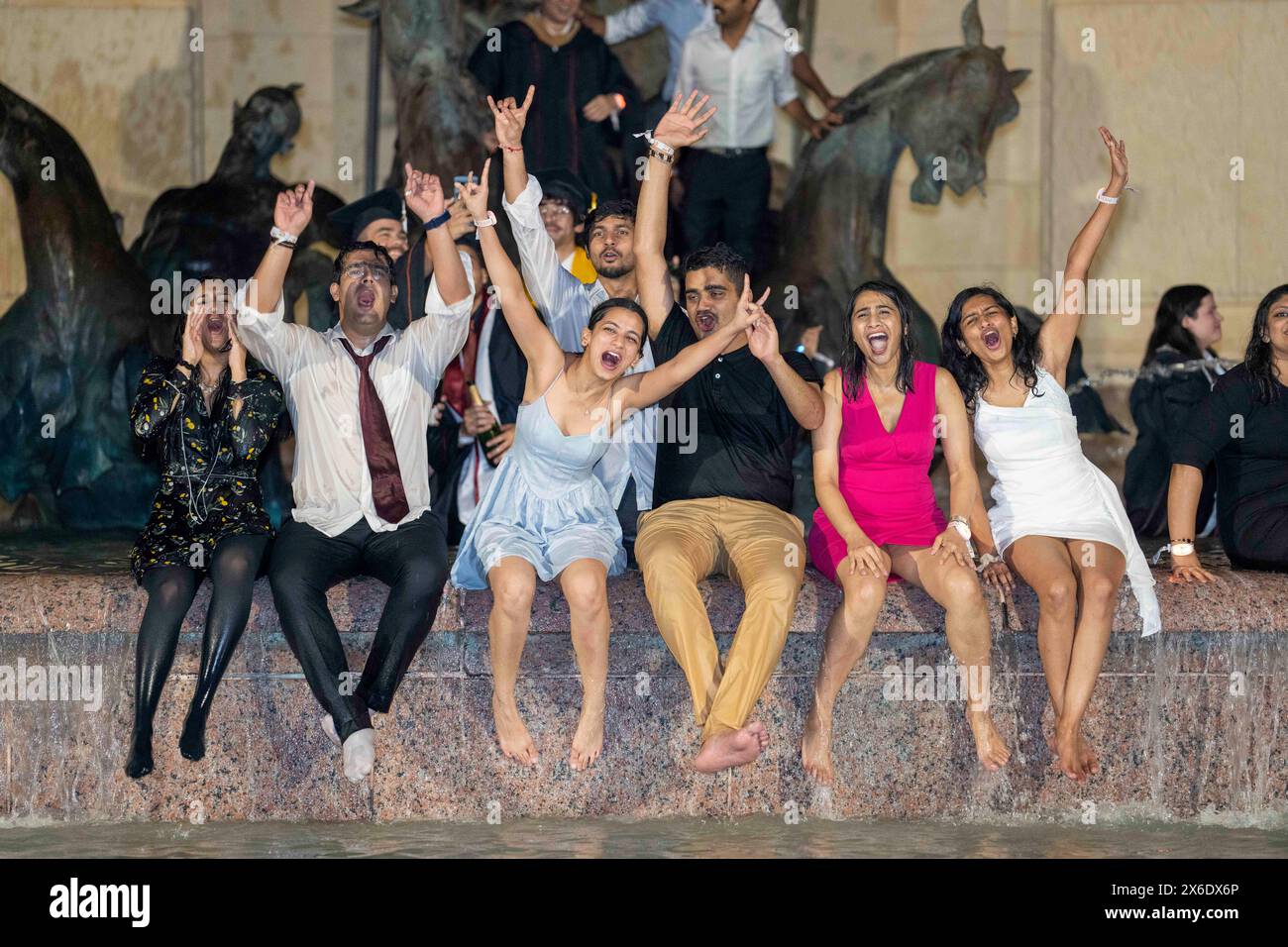 Austin Texas USA, May 11 2024: New University of Texas at Austin graduates whoop it up in the Littlefield Fountain immediately after their commencement ceremony held nearby in the school's football stadium. The celebratory dunk is a long-standing campus tradition. ©Bob Daemmrich Stock Photo