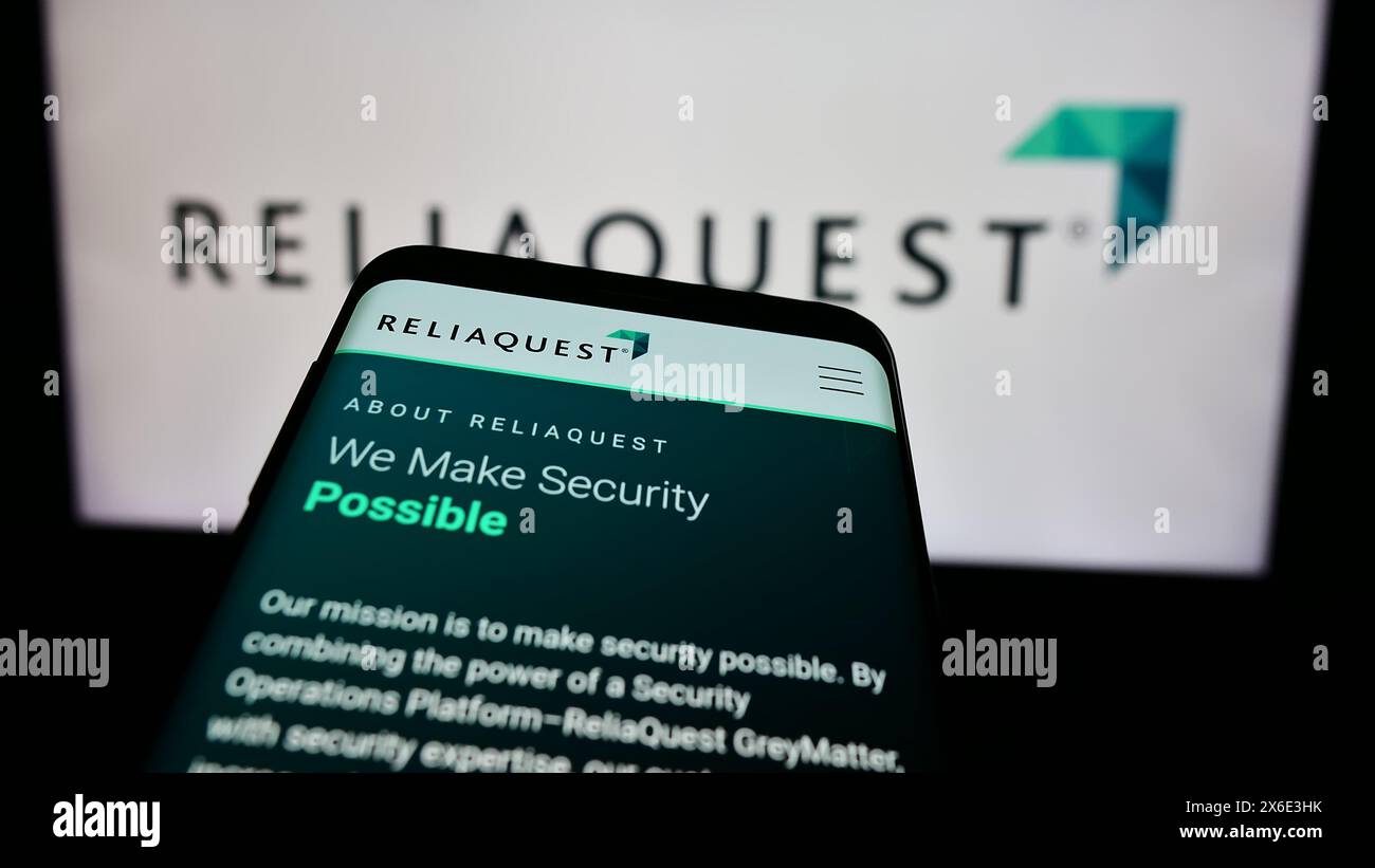 Mobile phone with website of US cybersecurity company ReliaQuest LLC in front of business logo. Focus on top-left of phone display. Stock Photo