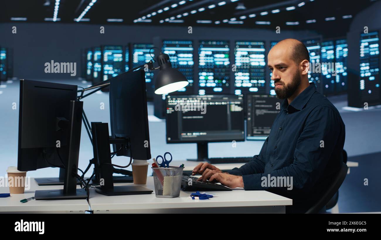 Man programming in high tech facility with server rows providing ...
