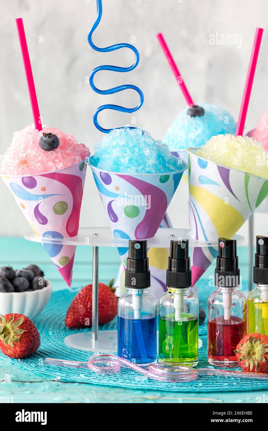 A vertical view of various snow cones with flavoured syrups in front