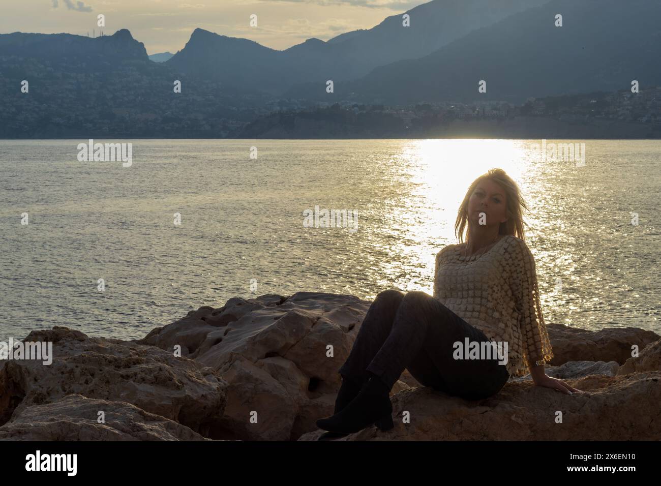 This portrait captures a woman in a moment of serene reflection on the rocky shores of Calpe, Spain. Stock Photo