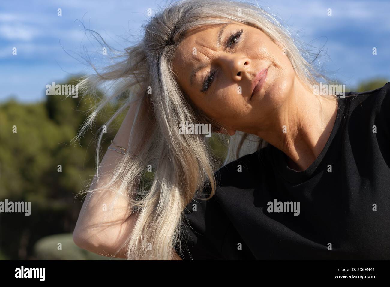 This portrait captures the essence of serene elegance as a woman stands enveloped in the soft embrace of nature’s light. Stock Photo