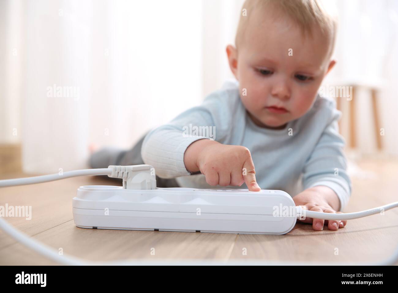 Little child playing with power strip on floor indoors, selective focus