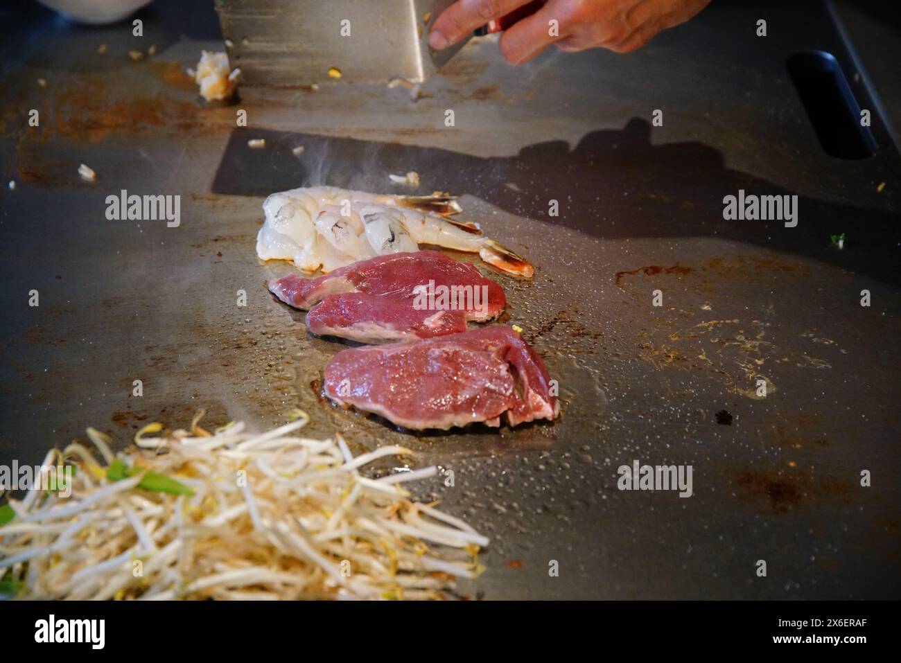 chef's hands with spatula over teppanyaki. cooking vegetables meat and ...