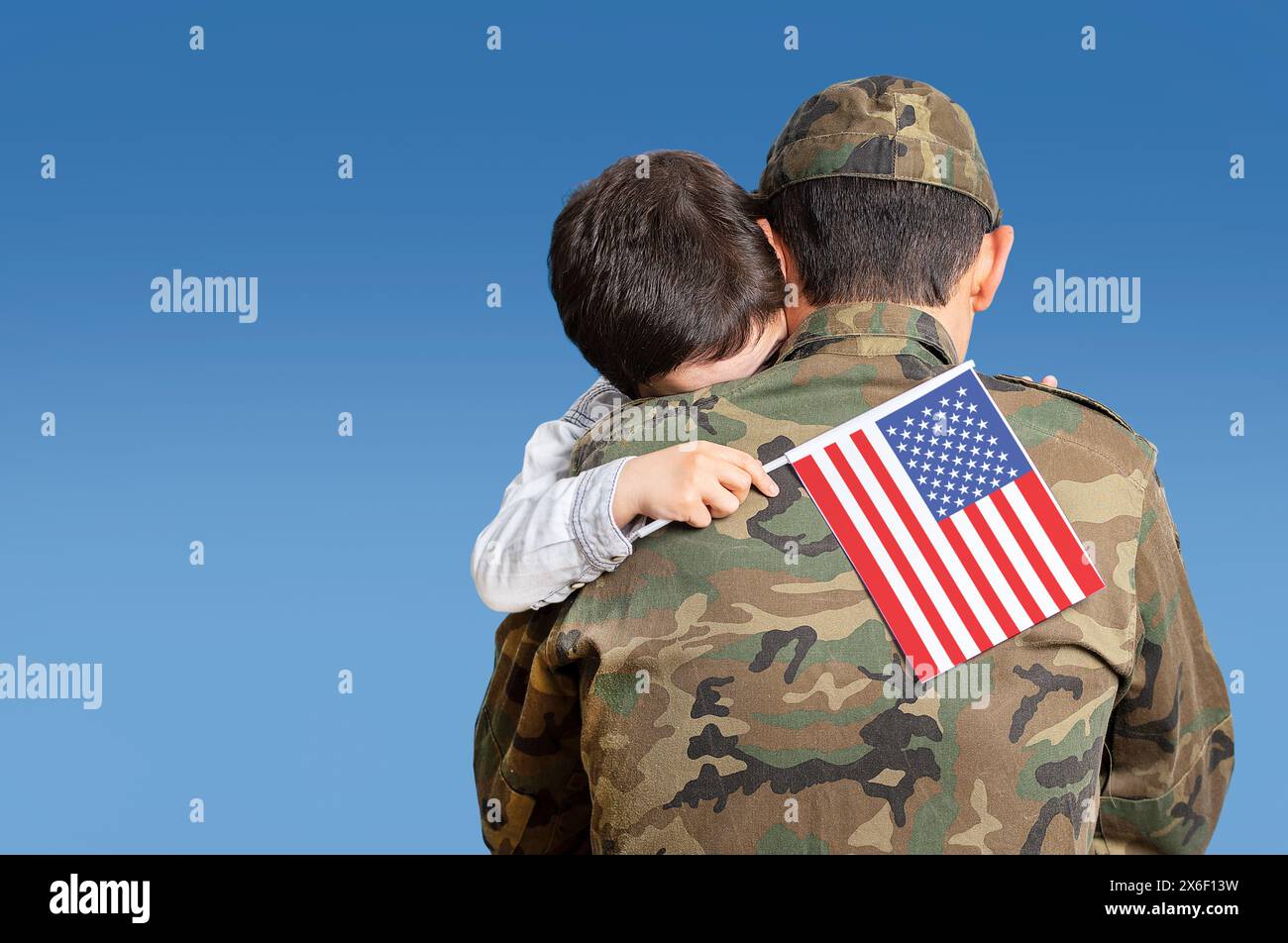 Shot of an adorable child hugging his father affectionately with the united states flag in his hand with a blue sky and copy space. Stock Photo