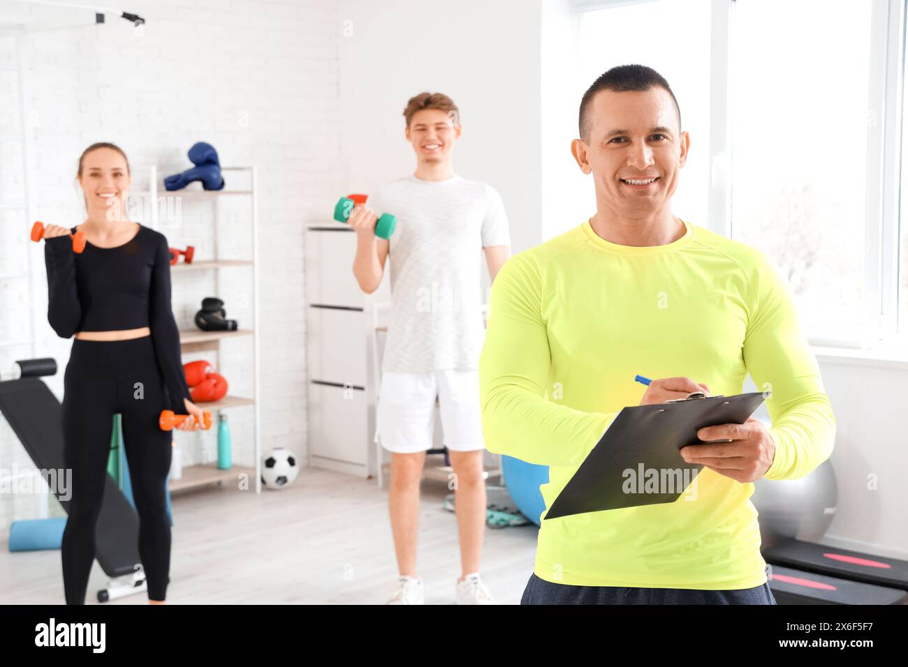 Male coach writing in clipboard at gym Stock Photo - Alamy