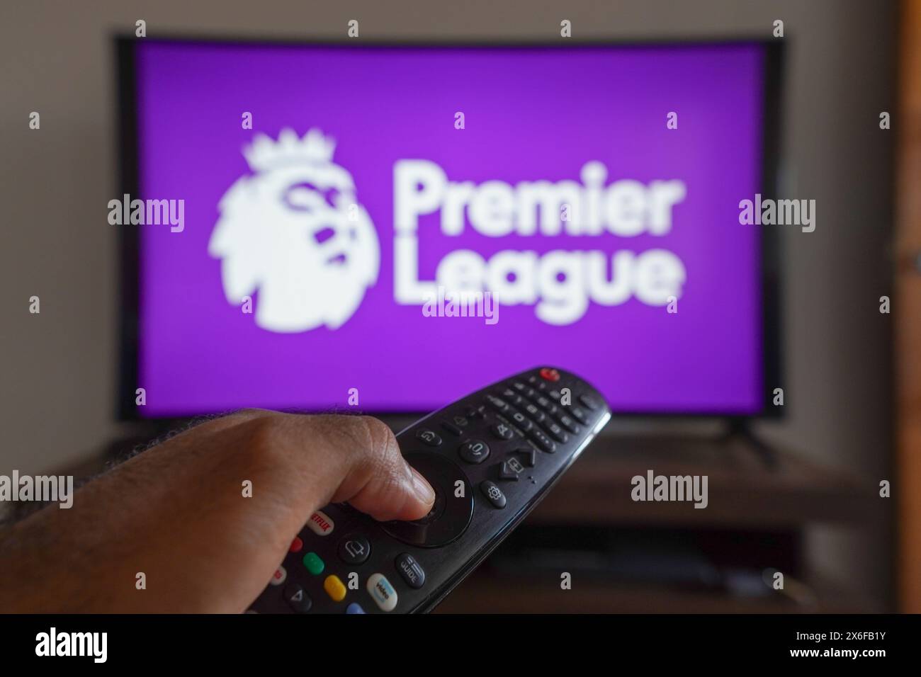 Brazil. 13th May, 2024. In this photo illustration, a hand holding a TV remote control in front of the Premier League logo on a TV screen. Credit: SOPA Images Limited/Alamy Live News Stock Photo