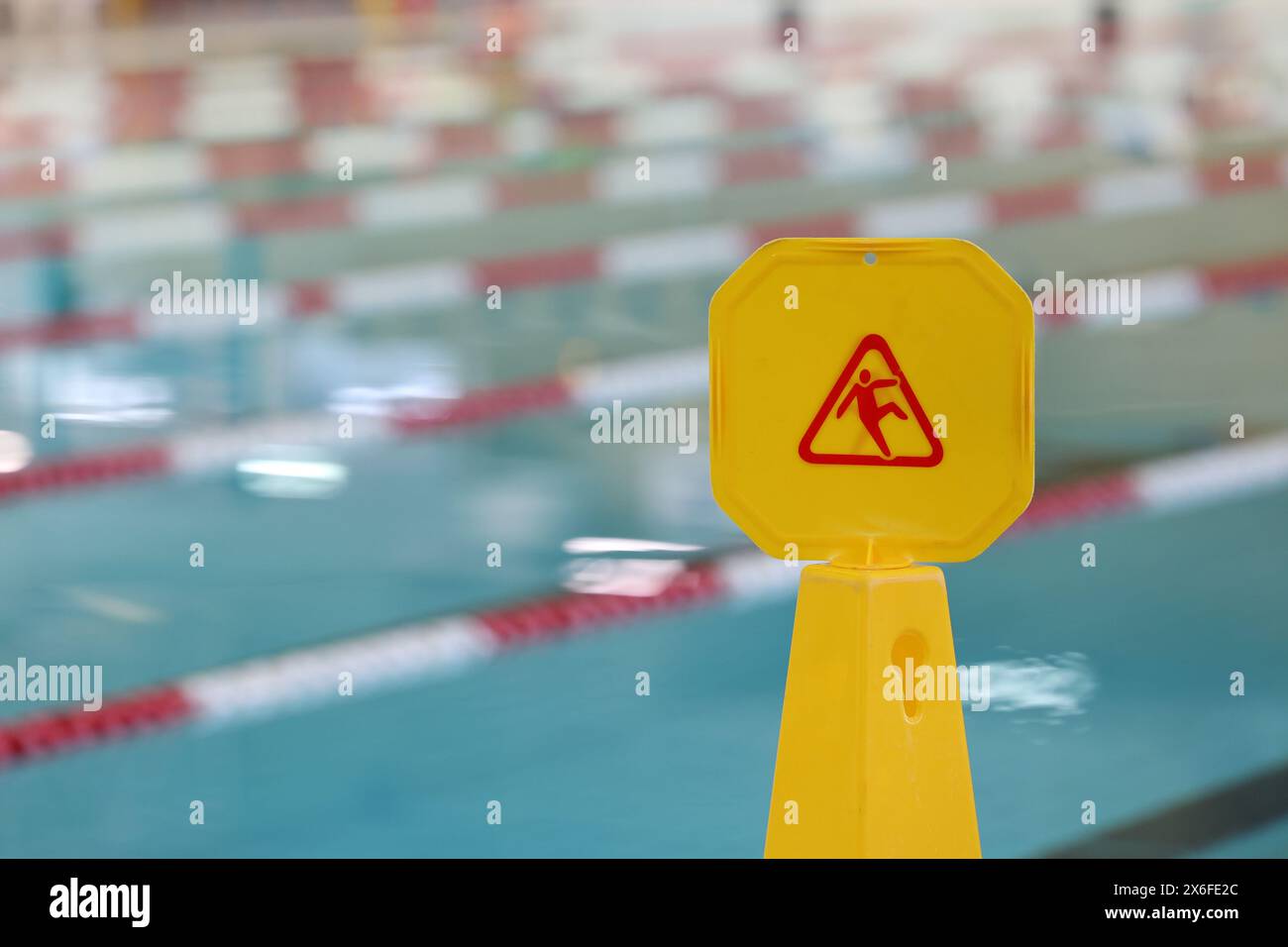 Yellow slip fall hazard sign at a public swimming pool. Public liability and insurance preventing accidents and injury. Stock Photo