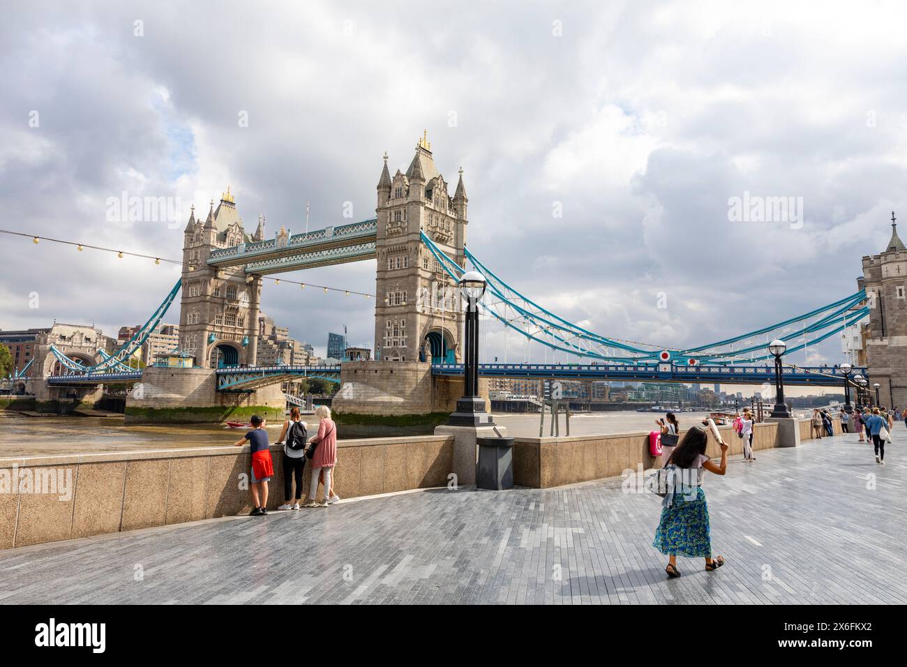 Tower Bridge London famous landmark, tourists sightseeing on Queens Walk South bank looking at the Grade 1 listed bridge structure,London,England,UK Stock Photo