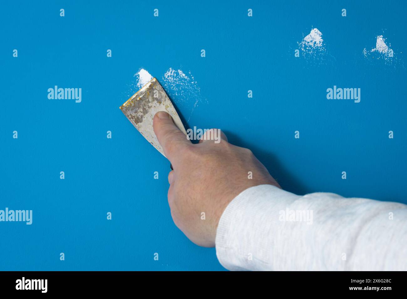 Small nail holes or deep scratches filling up with putty plaster in the wall before painting