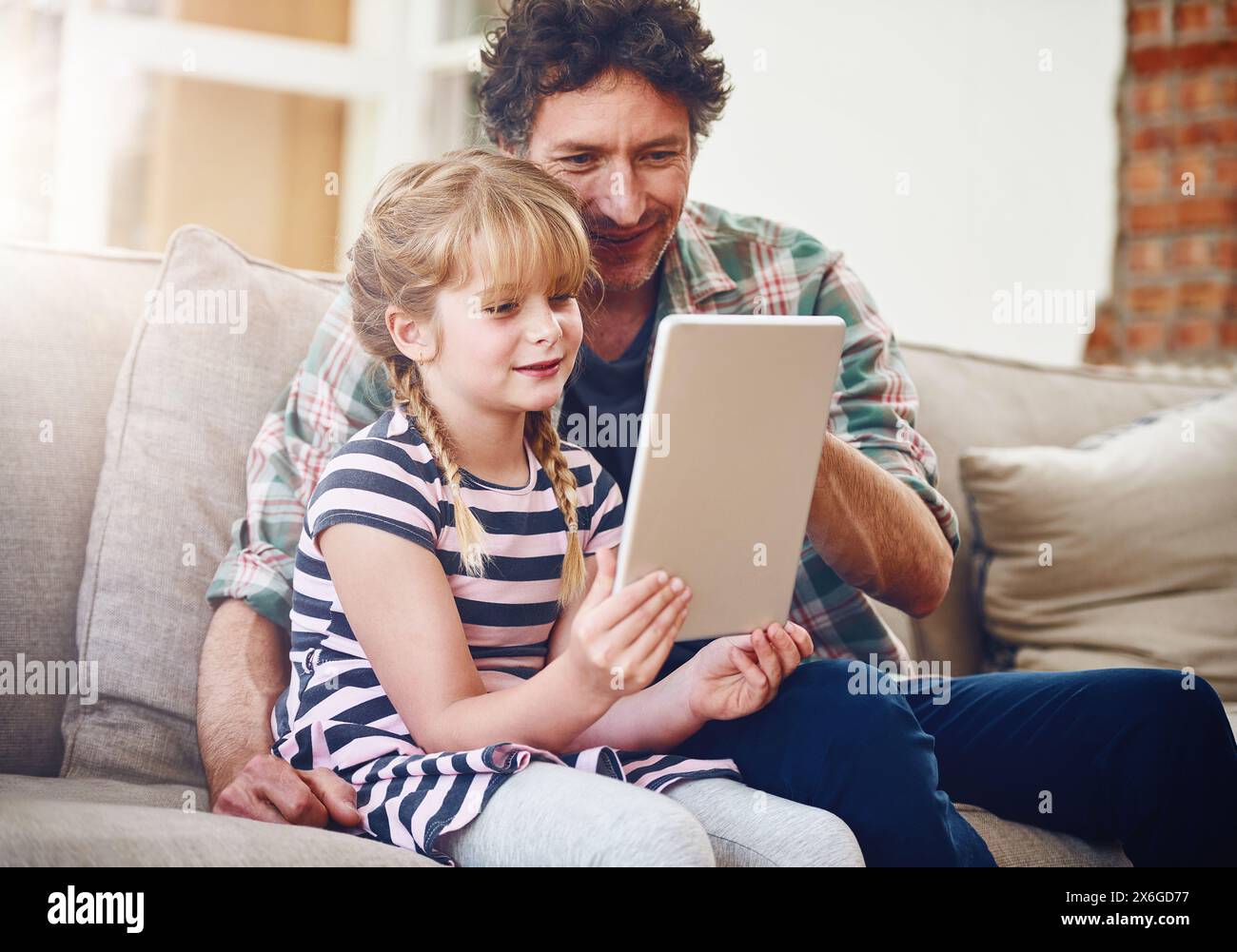 Home, dad and daughter with tablet in sofa with smile for elearning, child development and knowledge with growth. Parent, kid and support with help Stock Photo