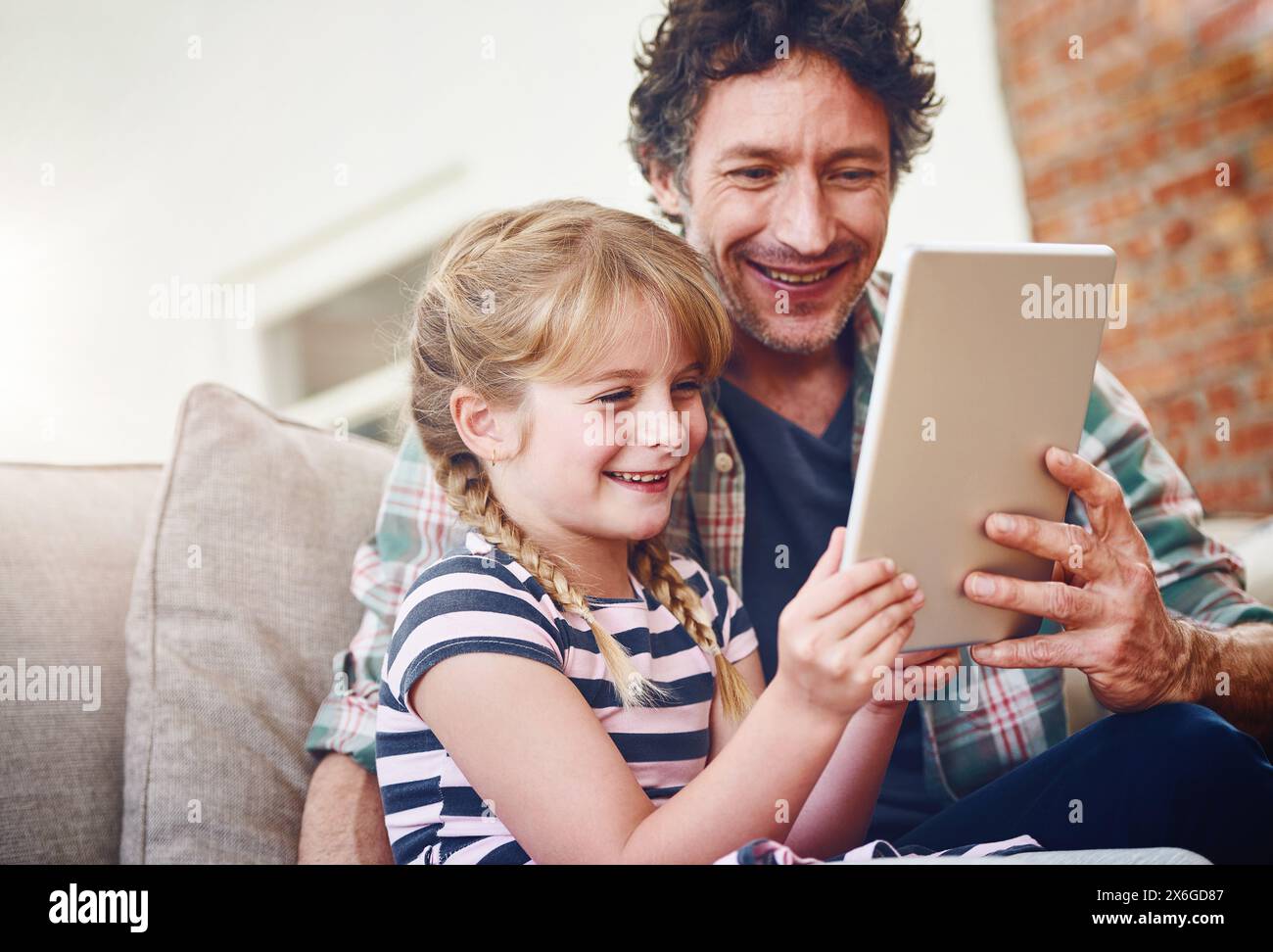 Smile, dad and girl with tablet in sofa at home for elearning, child development and knowledge with growth. Parent, kid and support with help Stock Photo