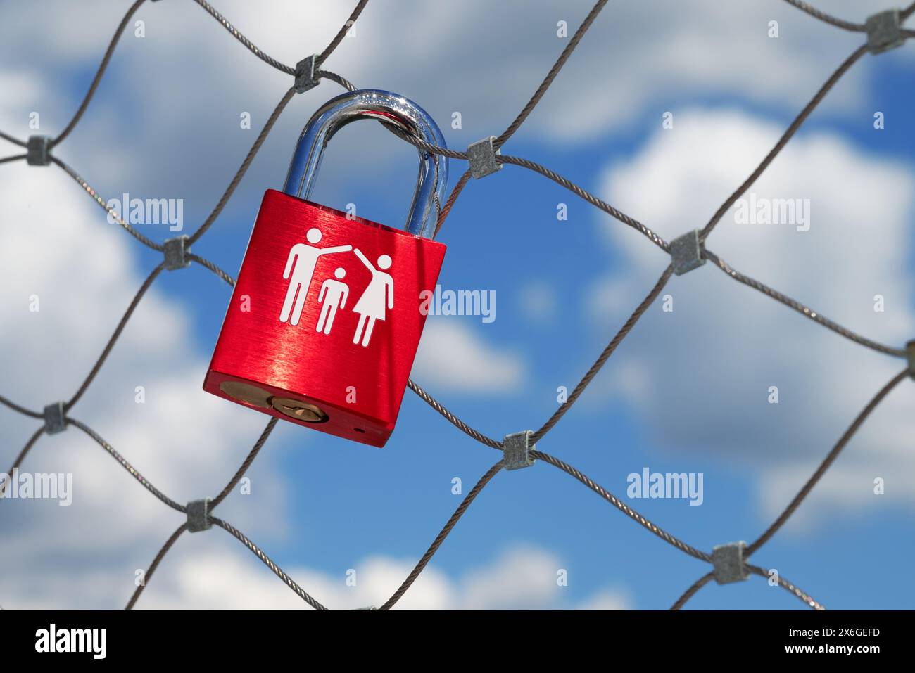 a single red love lock with a couple and a child hangs on a bridge railing Stock Photo