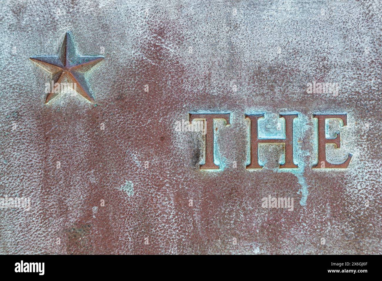 Star with patina. Star on a bronze monument. Inscription THE on a bronze plate. Close-up of definite article THE on a bronze slab with oxidized green Stock Photo