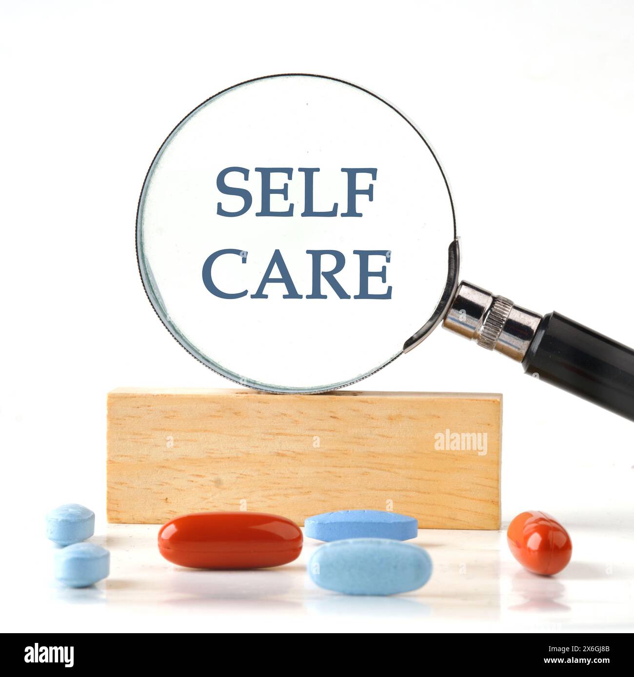 Take care of yourself. Self-care word it manifested itself in a magnifying glass standing on a wooden bar. The aspect ratio of the photo is 1 to 1 Stock Photo