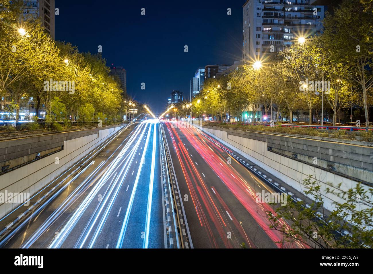 Panoramic nighttime view of the Paseo de la Castellana avenue in the city of Madrid, Spain, Europe. You can see the streaks of light from cars passing Stock Photo