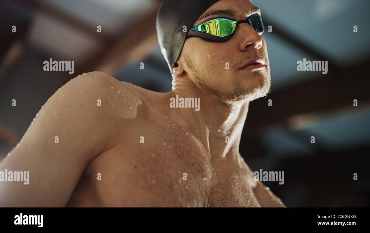 Handsome Professional Male Swimmer in Swimming Pool, Wearing Cap and Glasses, Looks Confidently at the Camera, Ready to Win the Championship. Portrait of Confident Man. Stock Photo