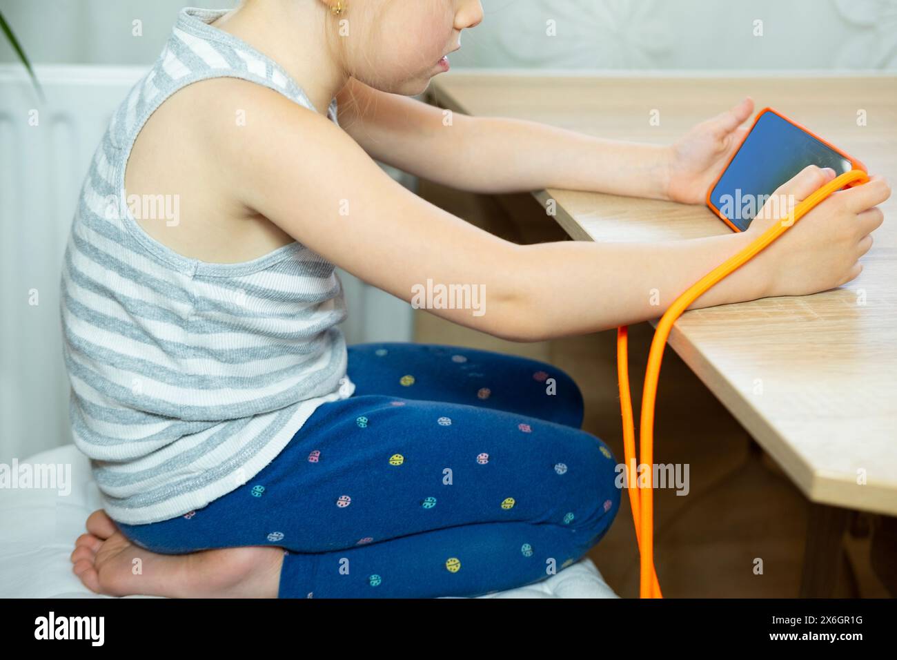 young girl Hunched over mobile device, child neglects physical posture, negative effects With neck craned and shoulders rounded Stock Photo