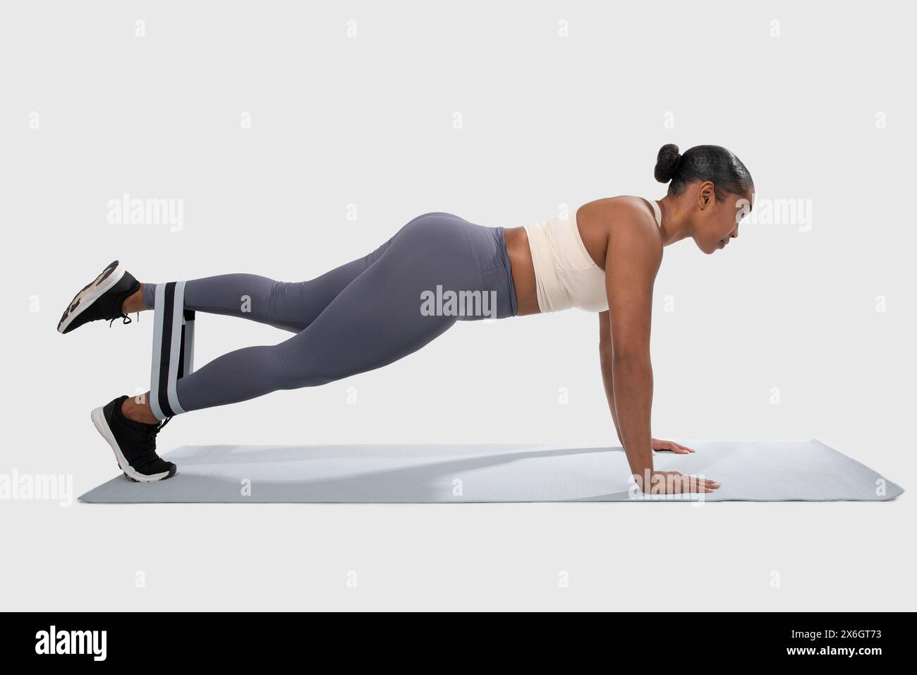 Woman Doing Push-Ups on Mat, Using Resistance Band Stock Photo