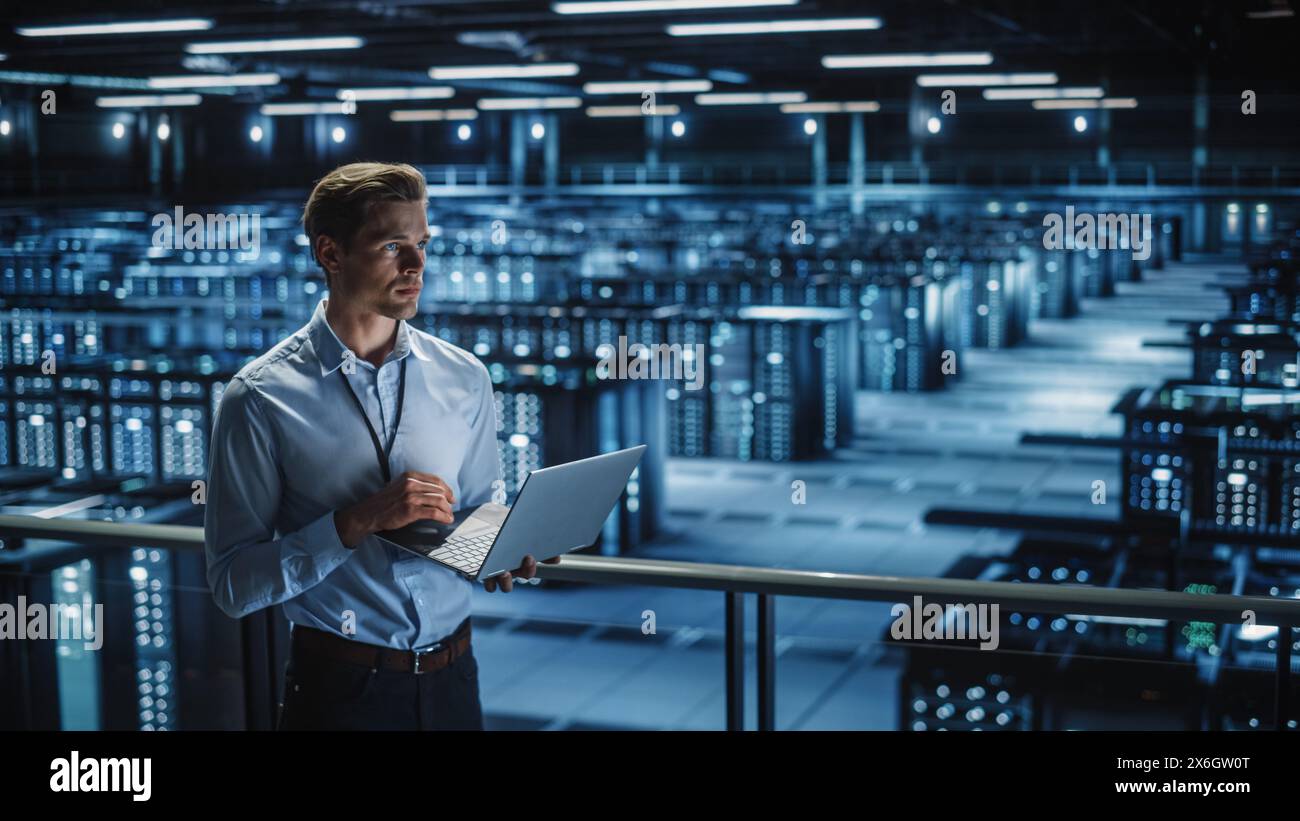 Data Center Specialist Engineer Using Laptop Computer. Server Farm Cloud Computing Facility with Male Maintenance Administrator Working. Data Protection Network for Cyber Security. Stock Photo