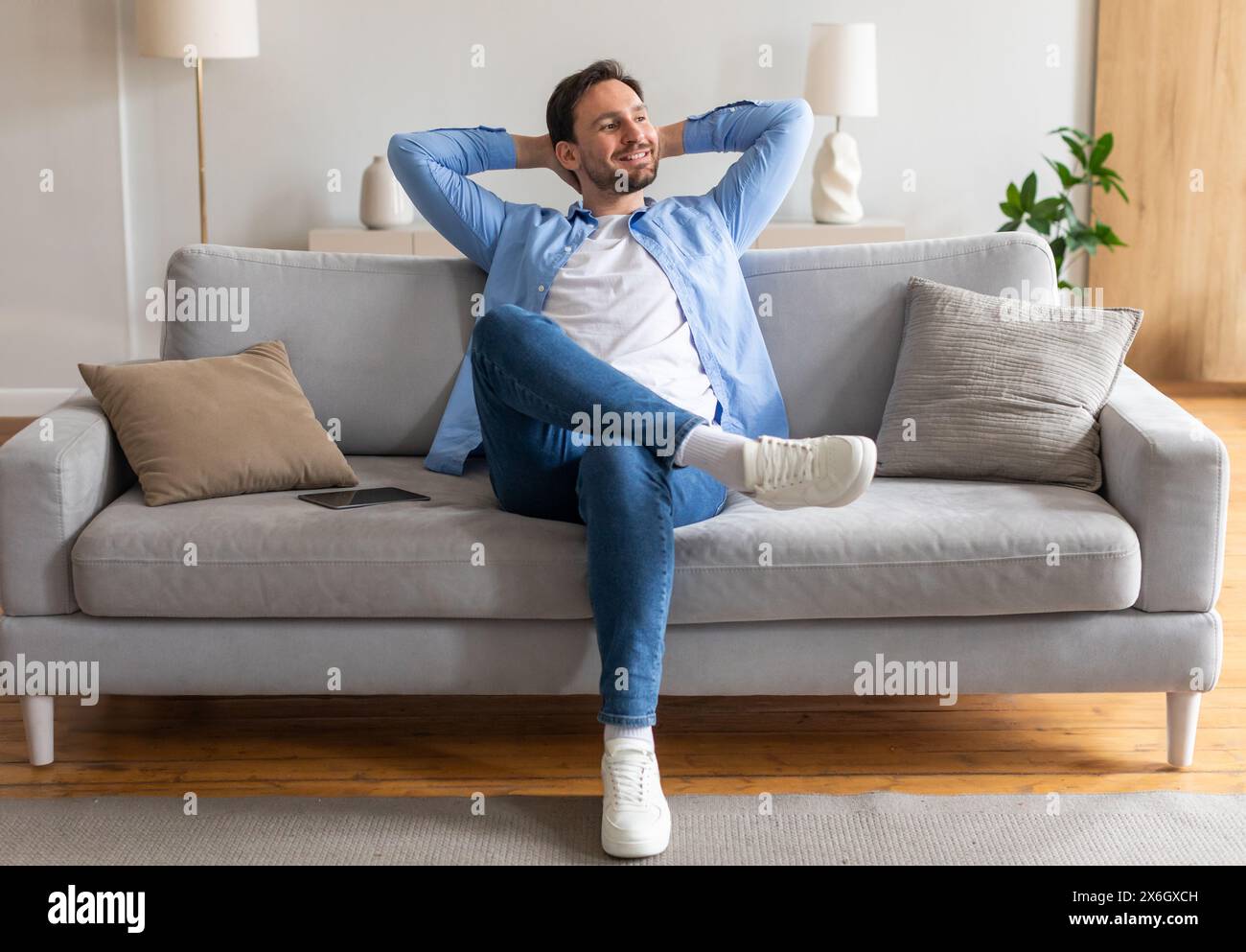 Man Sitting on Couch With Hands on Head Stock Photo