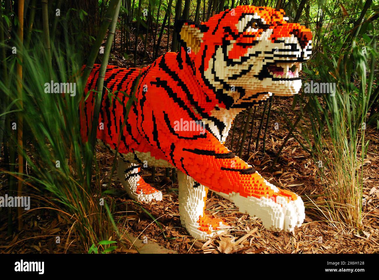 A striped tiger made of Legos appears to be emerging from the bushes at a display in the Bronx, New York Stock Photo