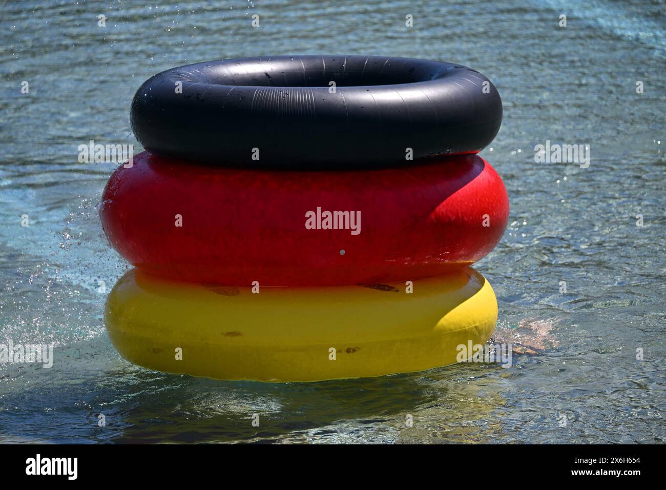 Weimar, Germany. 15th May, 2024. Three rubber tires in black, red and yellow lie in the water of
