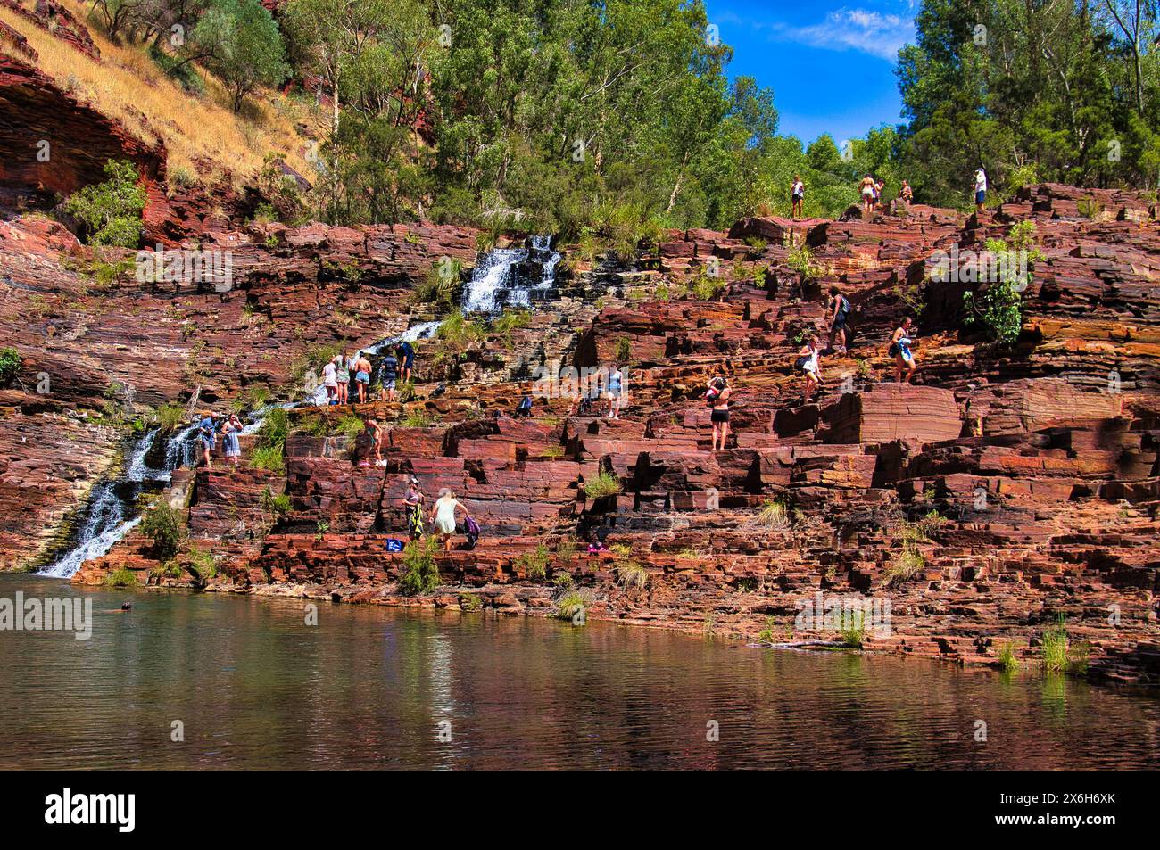 Dozens of people relaxing on the red rocks at Fortescue Falls . Dales ...